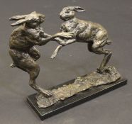 LUCY KINSELLA (1960-) "Fighting hares", signed bottom right, raised on a black marbled base, 28.