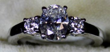 A platinum set three stone diamond ring, the central oval cut diamond approx 1.25 carats, flanked by