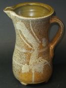 A Michael Casson mottled brown glazed jug of waisted form raised on four shaped feet, 24 cm high