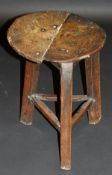 A 17th Century oak cricket table, the oval two plank top on splayed chamfered supports united by