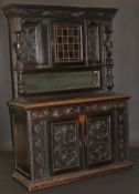 A Victorian Gothic Revival carved oak sideboard with green man masks, warriors, etc, the glazed