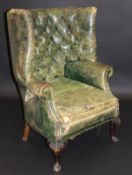 An early 20th Century barrel back armchair in green leather buttoned back upholstery with brass