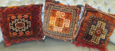 Three cushions with Caucasian carpet panels to fronts with red and black grounds