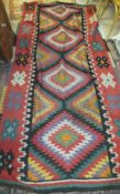 A Kelim rug with geometric design in red, black, yellow, green, orange, cream and purple,