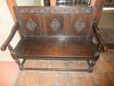 An oak settle with triple panel back with diamond shaped carving,