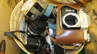 A circular basket containing a collection of camera equipment to include two Olympus OM10s,