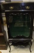 A circa 1900 ebonised display cabinet with drawer over a glazed door on cabriole legs united by an