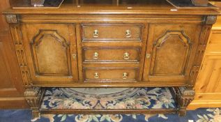 An oak sideboard with three short drawers flanked by cupboard door,