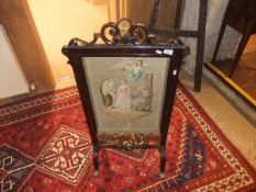 A 19th Century rosewood framed fire screen with petit point needlework decoration of figures with