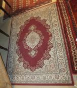 A Persian style machine made rug, the central cream medallion on a burgundy ground within cream,