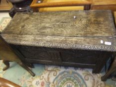 A 17th Century oak coffer, the top with later carved edge over a carved two panelled front,