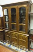 An oak display cabinet with three glazed doors enclosing shelves on a base of two cupboard doors