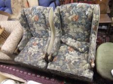 A pair of early 20th Century oak framed wing back chairs in foliate patterned upholstery