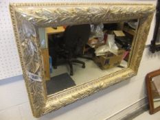 A large rectangular wall mirror with gesso frame decoration with moulded leaves and berries