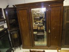 A Victorian mahogany wardrobe compactum with central mirrored door flanked by two cupboard doors