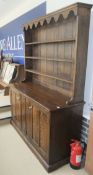 An oak dresser, the three tier boarded plate rack above two pairs of doors with painted decoration