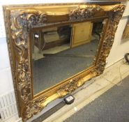 A large modern gilt moulded wall mirror with rectangular bevel edged plate