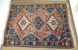 A Persian rug, the three diamond shaped linked medallions on a salmon ground within blue,