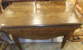 An oval drop-leaf oak dining table on square tapering legs