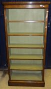 A tall oak bookshelf with adjustable shelving on a plinth base