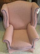 A child's wing back armchair upholstered in red and cream checked fabric,