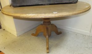 A circular pine kitchen table raised on baluster turned support to tripod base
