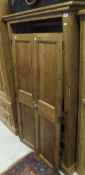 A pine wardrobe, the two doors enclosing hanging space and shelves under,