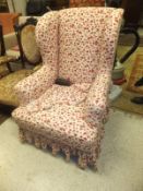 An Edwardian wing back armchair raised on ringed and turned legs