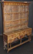 An 18th Century Welsh oak dresser, the boarded plate rack with stepped cornice above a set of cup