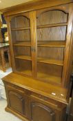 An oak display cabinet with two doors enclosing various shelving over two drawers and two cupboard