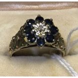 A 9 carat gold diamond and sapphire set cluster ring with textured shoulders