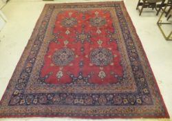 A Persian rug, the central burgundy ground with stylised floral motifs in dark blue, pink,