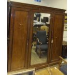 A Victorian mahogany wardrobe compactum with central mirrored door flanked by two cupboard doors