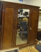 A Victorian mahogany wardrobe compactum with central mirrored door flanked by two cupboard doors