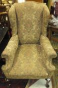 A pair of 1920's upholstered wing back scroll armchairs on cabriole front legs to pad feet in the