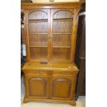 An oak display cabinet with two doors enclosing various shelving over two drawers and two cupboard
