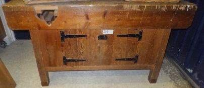 A pine top work bench with various cupboard doors under