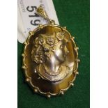 A 9 carat gold mounted tigers eye pendant set with central relief work bust of woman with flowers