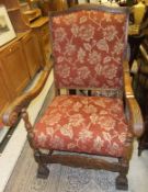 An early 20th Century Flemish style oak framed open arm elbow chair with carved acanthus decorated