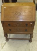 A 20th Century oak bureau of two drawers with applied moulded decoration