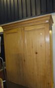 A waxed pine two door wardrobe on single drawer to base