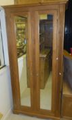 A pine two door wardrobe, the shaped cornice over above two glazed doors,
