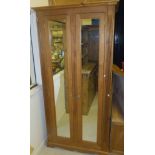 A pine two door wardrobe, the shaped cornice over above two glazed doors,