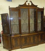 A large mahogany breakfront display cabinet with broken swan neck pediment above four sets of