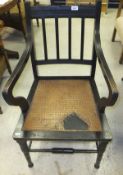 A circa 1900 ebonised framed elbow chair on turned and ringed legs united by stretchers