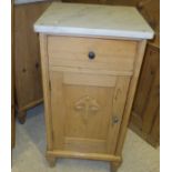 A pair of pine single door bedside cupboards with marble tops