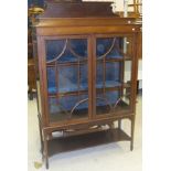 An Edwardian mahogany Sheraton Revival display cabinet with two glazed doors enclosing two shelves,