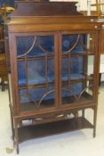 An Edwardian mahogany Sheraton Revival display cabinet with two glazed doors enclosing two shelves,