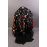 A black and multi coloured silk floral embroidered shawl with deep tasseled fringe