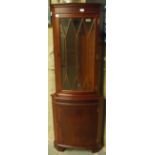 A reproduction mahogany corner cupboard with glazed upper section and panelled cupboard below on